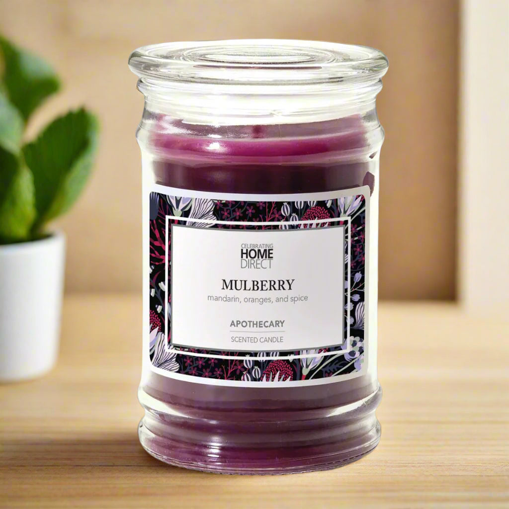Purple Mulberry candle in a glass jar with a decorative label on a wooden table
