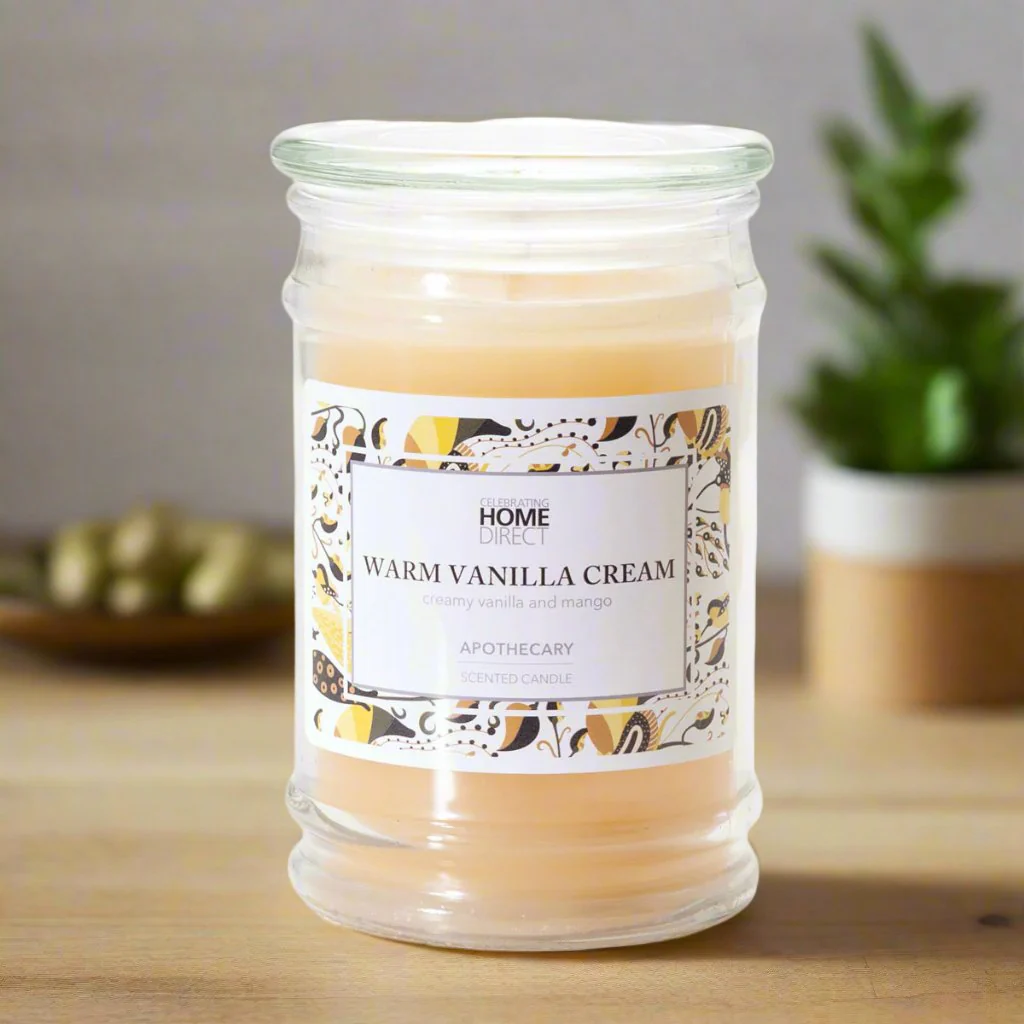A 17 oz jar candle with a creamy vanilla fragrance and sugar mango accent, set on a table with a decorative label on top.
