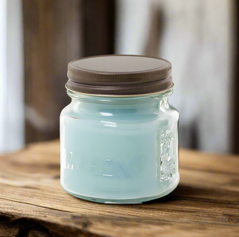 A blue tinted Mason jar candle with a brown lid, sitting on a wooden surface.